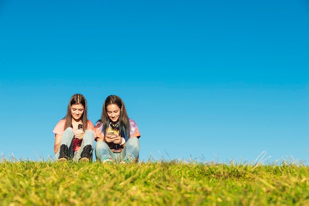 Duas lindas adolescentes usando o celular no parque