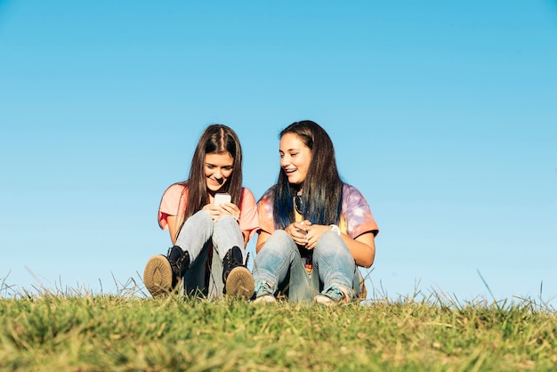 Duas lindas adolescentes usando o celular no parque