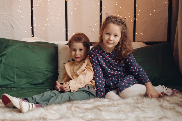 Duas lindas crianças sentadas na cama juntas