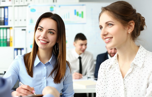 Duas lindas funcionárias brancas, sorrindo, discutindo no escritório um retrato de problemas de negócios