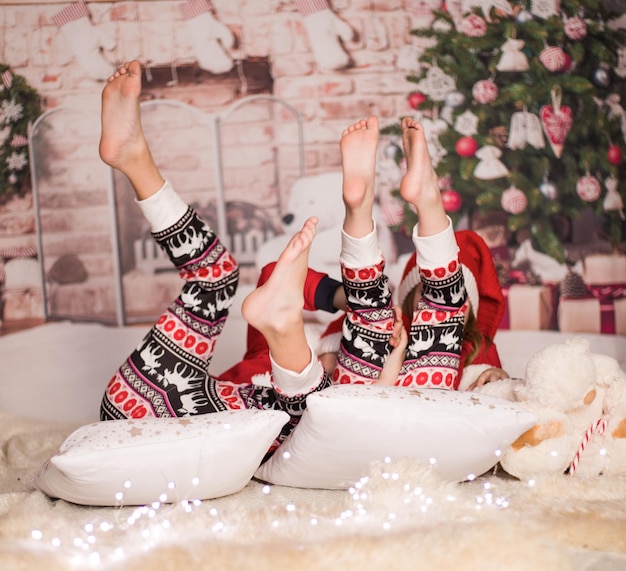 Duas lindas garotas alegres em roupas de Natal contra o fundo da árvore de Natal
