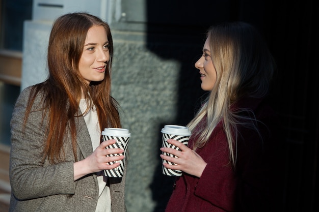 duas lindas garotas de cabelo comprido tomando café na cidade