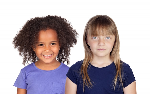 Duas lindas garotas de diferentes raças olhando para uma câmera isolada em um espaço em branco