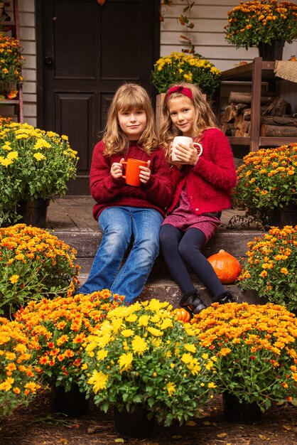 duas lindas garotas estão bebendo chá na rua em roupas quentes no outono conceito de halloween