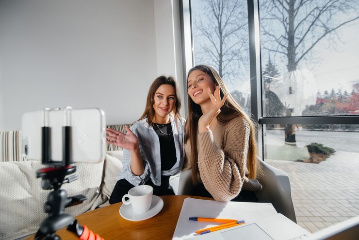 Foto duas lindas garotas estão sentadas em um café, gravando blogs de vídeo e se comunicando nas redes sociais.