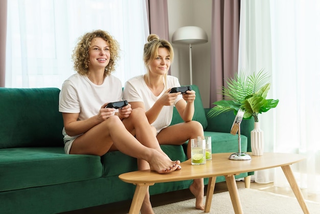 Duas lindas garotas jogando videogame na sala de estar de um apartamento moderno