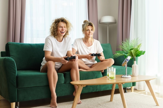 Duas lindas garotas jogando videogame na sala de estar de um apartamento moderno