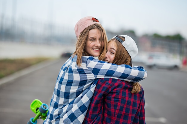 duas lindas garotas loiras sorridentes vestindo camisetas xadrez, bonés e shorts jeans