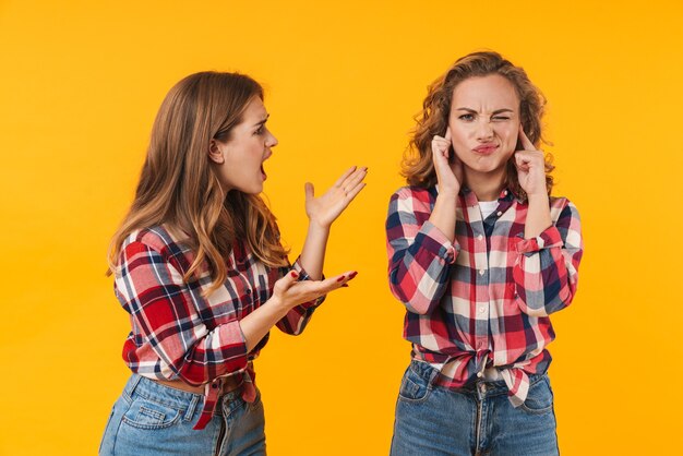 Duas lindas garotas vestindo camisa xadrez gritando e lutando isoladas