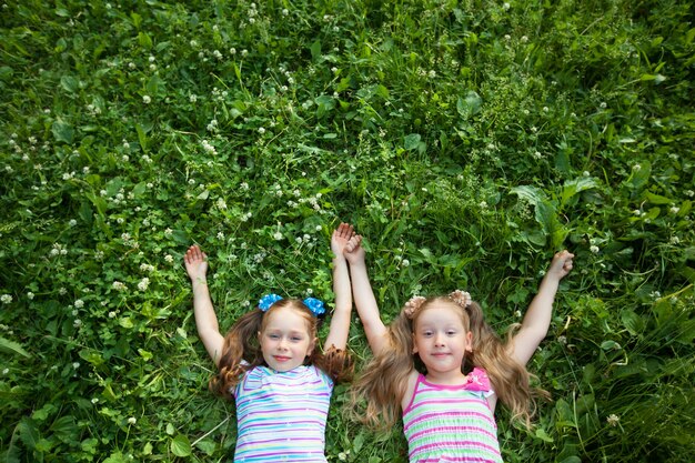 duas lindas garotinhas deitadas na grama verde no parque de verão