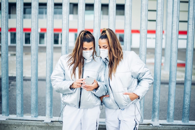 Duas lindas irmãs gêmeas usando smartphone