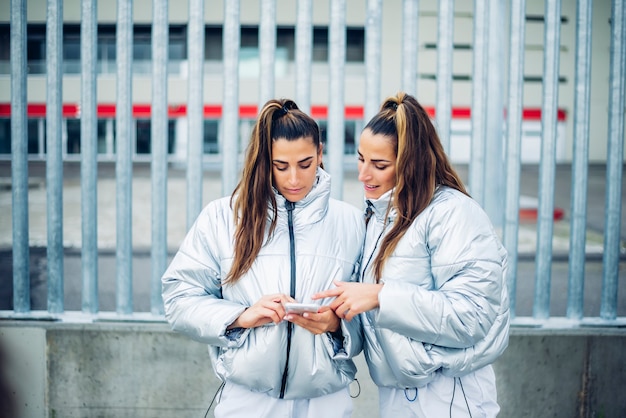 Duas lindas irmãs gêmeas usando smartphone