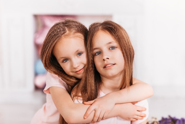 Duas lindas irmãs se abraçam em uma sala iluminada