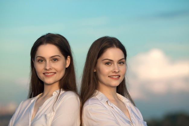 duas lindas jovens irmãs gêmeas no céu azul