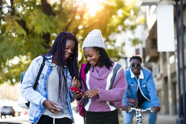 Duas lindas jovens usando o telefone celular na rua.