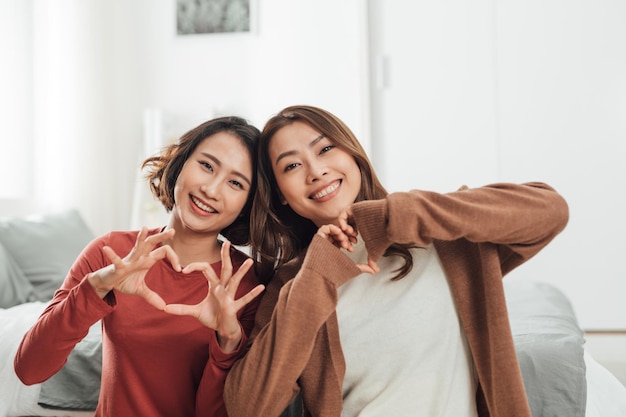 Duas lindas lésbicas estão se abraçando com mulheres amam e mostram o coração.