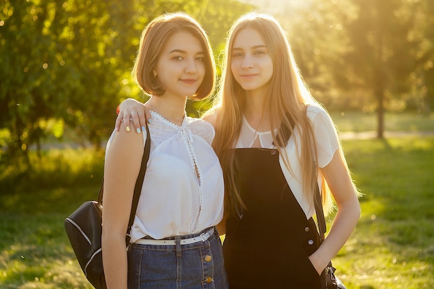 Duas lindas melhores amigas colegiais (estudante) se encontrando no parque