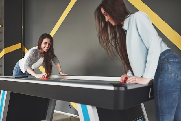 Duas lindas meninas gêmeas jogam air hockey no jogo e se divertem