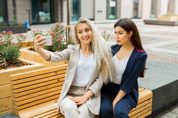 duas lindas moças de terno são fotografadas ao telefone