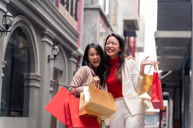 Duas lindas mulheres asiáticas com sacolas de compras na cidade sobre o fundo do shopping