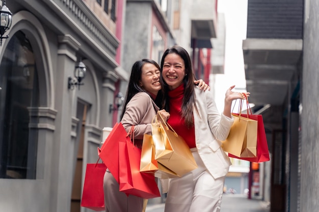 Duas lindas mulheres asiáticas com sacolas de compras na cidade sobre o fundo do shopping