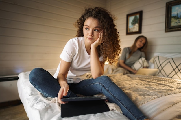 Duas lindas mulheres deitadas na cama segurando um laptop
