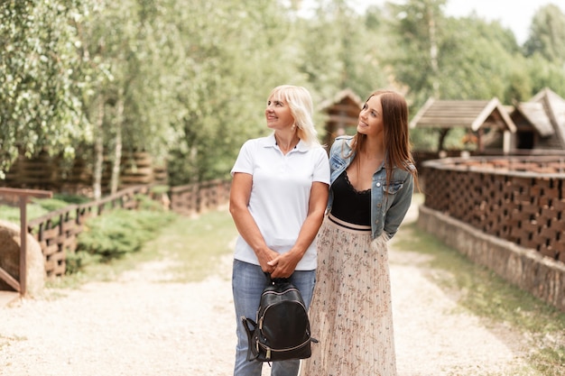 Duas lindas mulheres, mãe e filha em roupas da moda casual, estão caminhando na natureza no parque