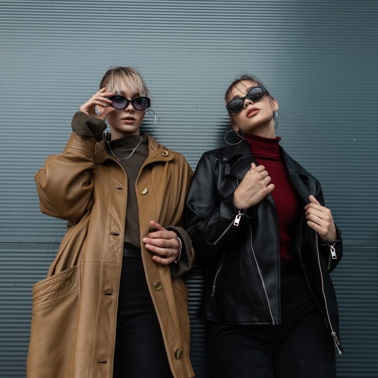 Foto duas lindas mulheres modelo adolescente em uma jaqueta de couro preta com jeans preto e óculos de sol posam perto de uma parede de metal