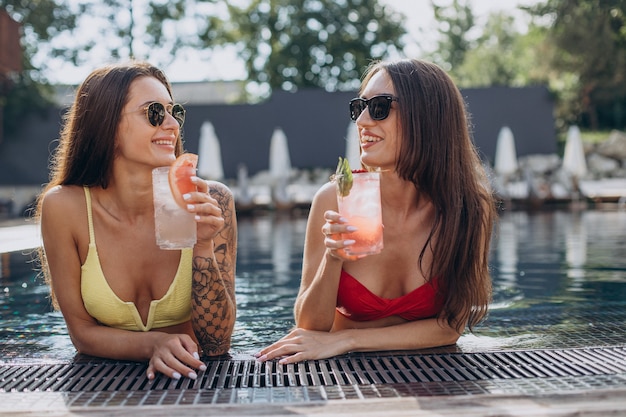 Duas lindas mulheres na piscina tomando coquetel