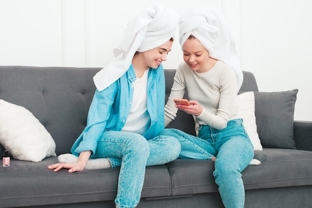 Duas lindas mulheres sorridentes sentadas no sofá