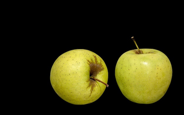 Duas maçãs verdes maduras em um fundo preto