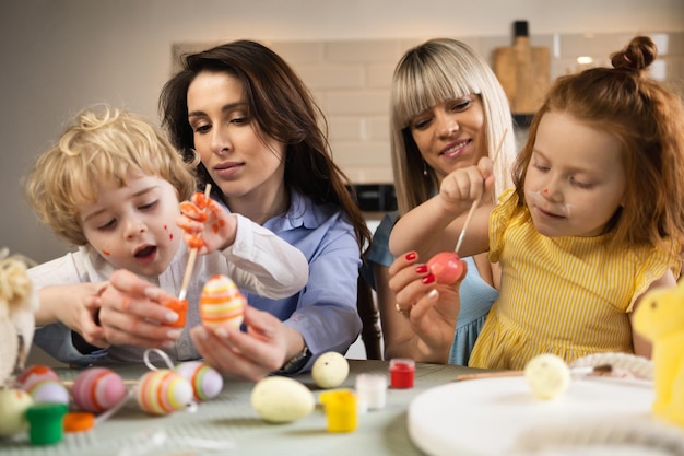 Duas mães com seus filhos colorem ovos em preparação para a Páscoa