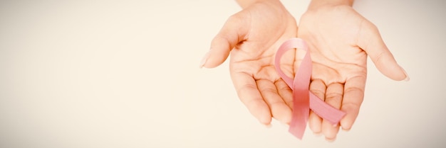 Duas mãos exibindo uma fita rosa para a conscientização do câncer de mama