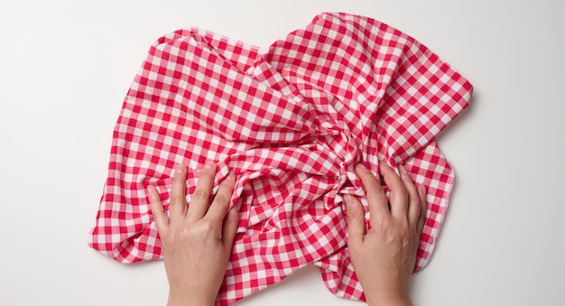 Duas mãos femininas segurando um guardanapo vermelho sobre uma mesa branca, vista superior