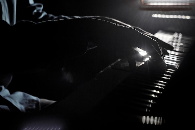 Foto duas mãos masculinas nas palmas das mãos do piano estão nas teclas e tocam o instrumento do teclado na escola de música que o aluno aprende a tocar as mãos do pianista preto fundo escuro