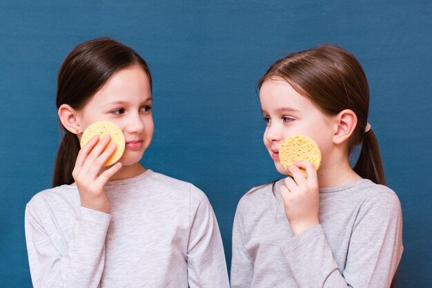 Duas meninas alegres lavando seus rostos com esponjas