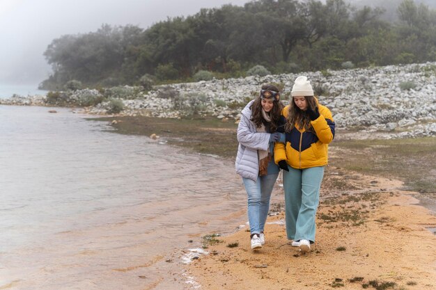 Duas meninas andando na margem de um lago em uma geleira