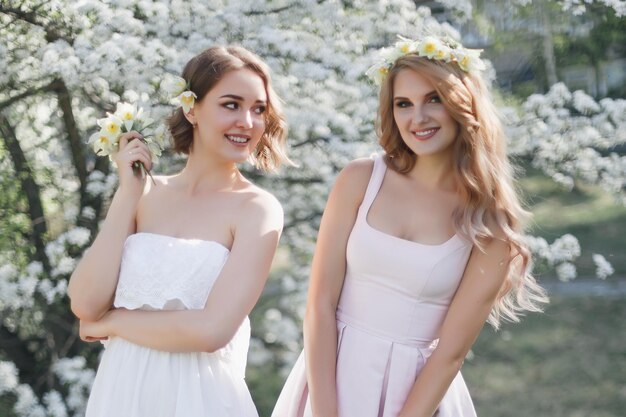 Duas meninas andando no parque onde as cerejeiras florescem as meninas vestindo vestidos de verão