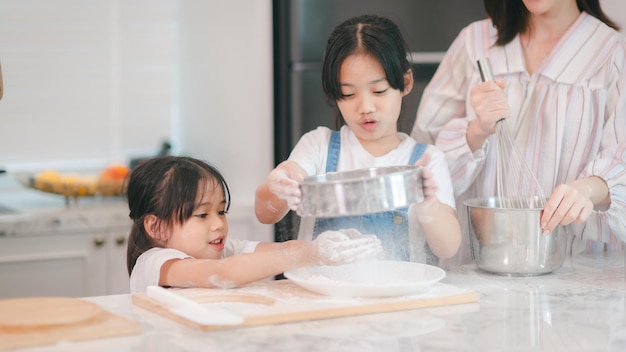 Duas meninas asiáticas bonitas aprendendo a fazer pão e padaria com um sorriso curioso e feliz Ela aprende e brinca