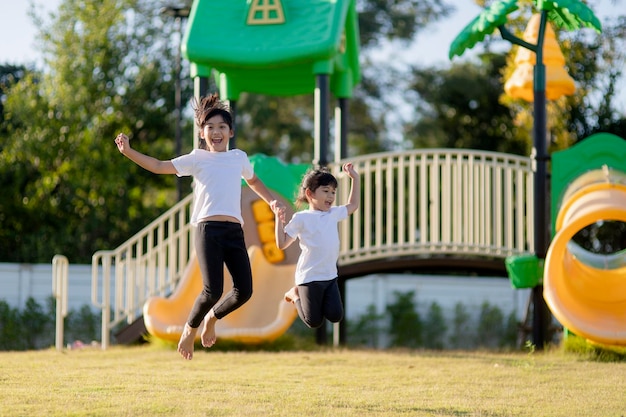Duas meninas asiáticas se divertindo em um playground ao ar livre no verão
