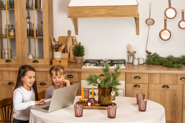 Duas meninas assistindo a escola online enquanto está sentado à mesa da mesa da sala de jantar.