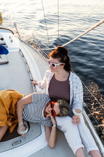 Duas meninas bebendo vinho e relaxando no veleiro durante a navegação no mar