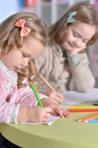 Duas meninas bonitas a desenhar com lápis.