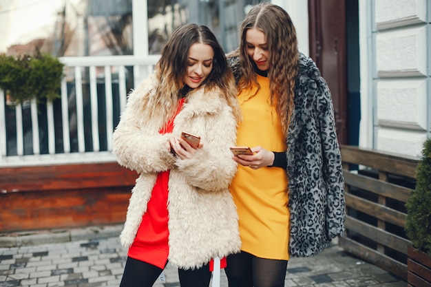 duas meninas bonitas e elegantes em roupas de moda estão andando na cidade de primavera