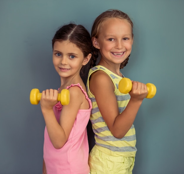 Duas meninas bonitinha estão segurando halteres