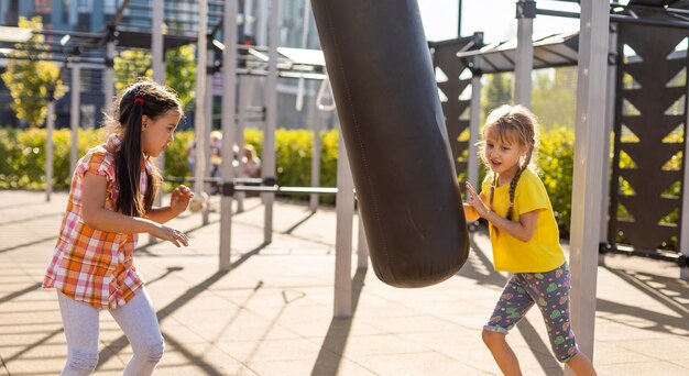 Duas meninas bonitinhas se divertindo em um playground ao ar livre no verão. Atividades esportivas para crianças.