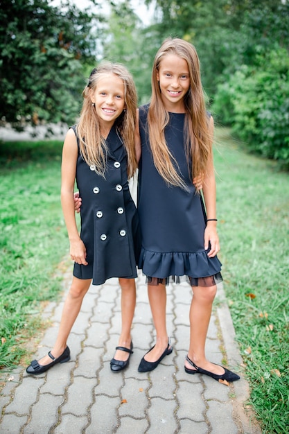 Duas meninas bonitinhas smilling posando na frente de sua escola.