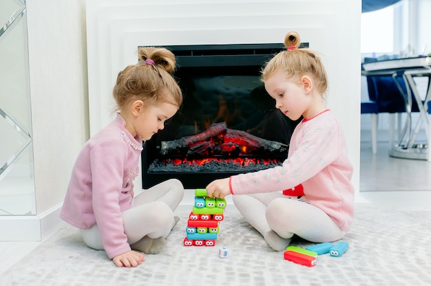 Duas meninas bonitos jogar um jogo de tabuleiro em uma casa aconchegante perto da lareira