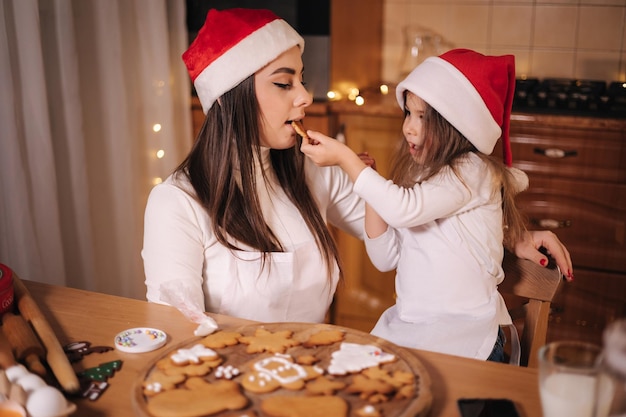 Duas meninas com chapéu de Papai Noel passaram o tempo muito felizes na cozinha nas férias de Natal