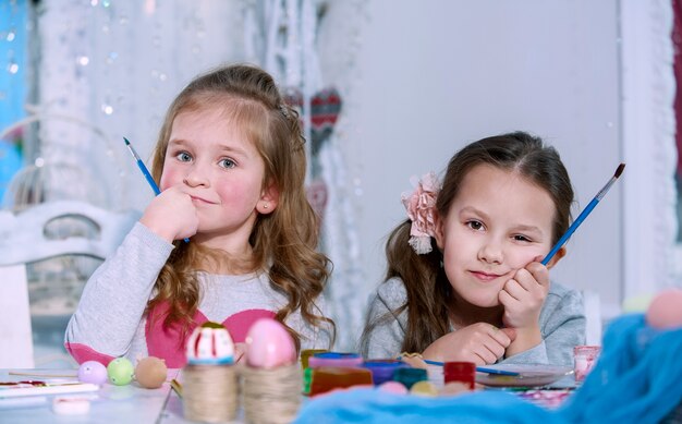 Duas meninas com pincéis nas mãos pensando e não sabem o que desenham. crise criativa do conceito.